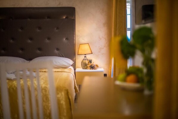 A bedroom with a tufted headboard, a bedside table with a lamp, and a small plant.