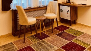 Ein gemütliches Zimmer mit einer hölzernen Sitzbank, zwei Stühlen, einem kleinen Tisch, einem Heizkörper und einem Spiegel an der Wand.