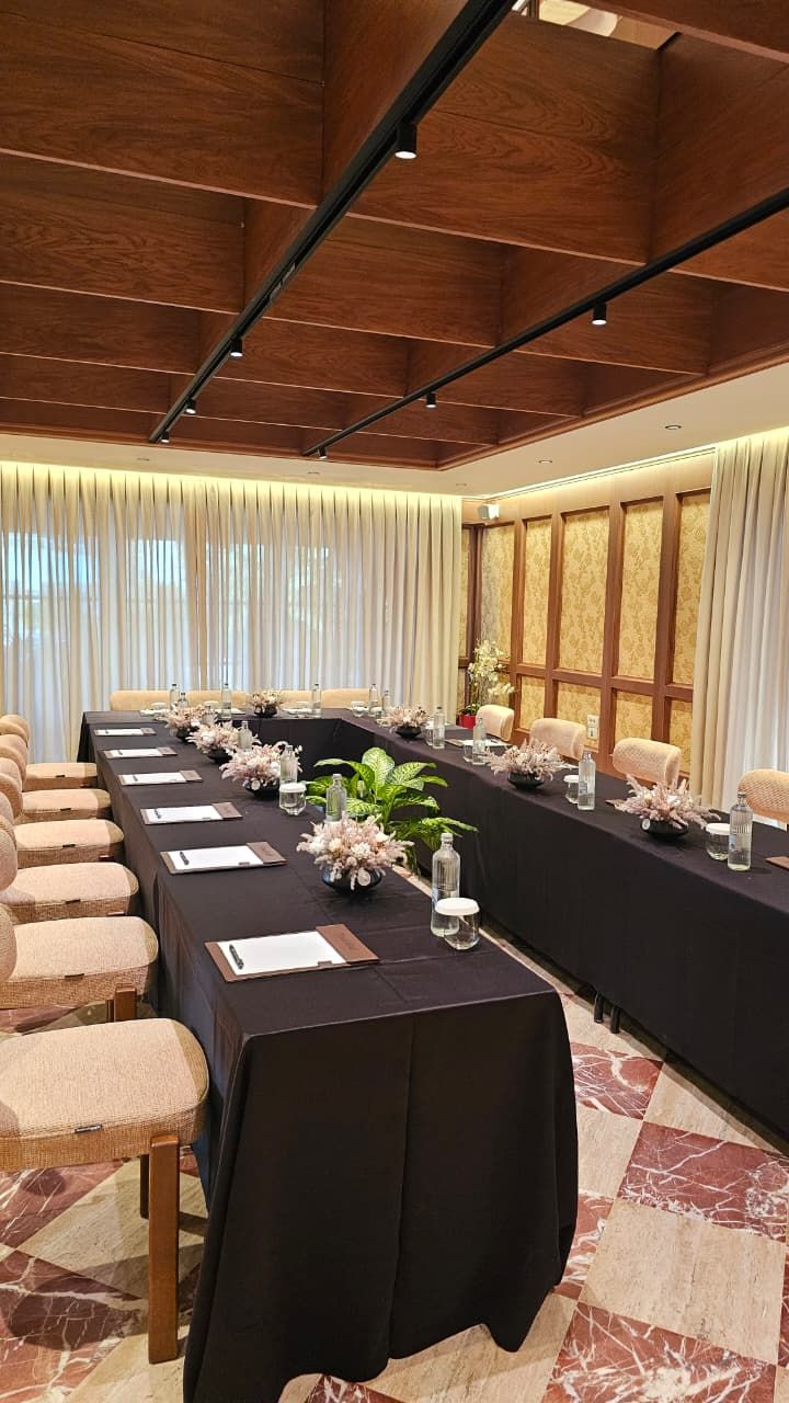 Une salle de conférence avec une longue table, des chaises et un plafond en bois.