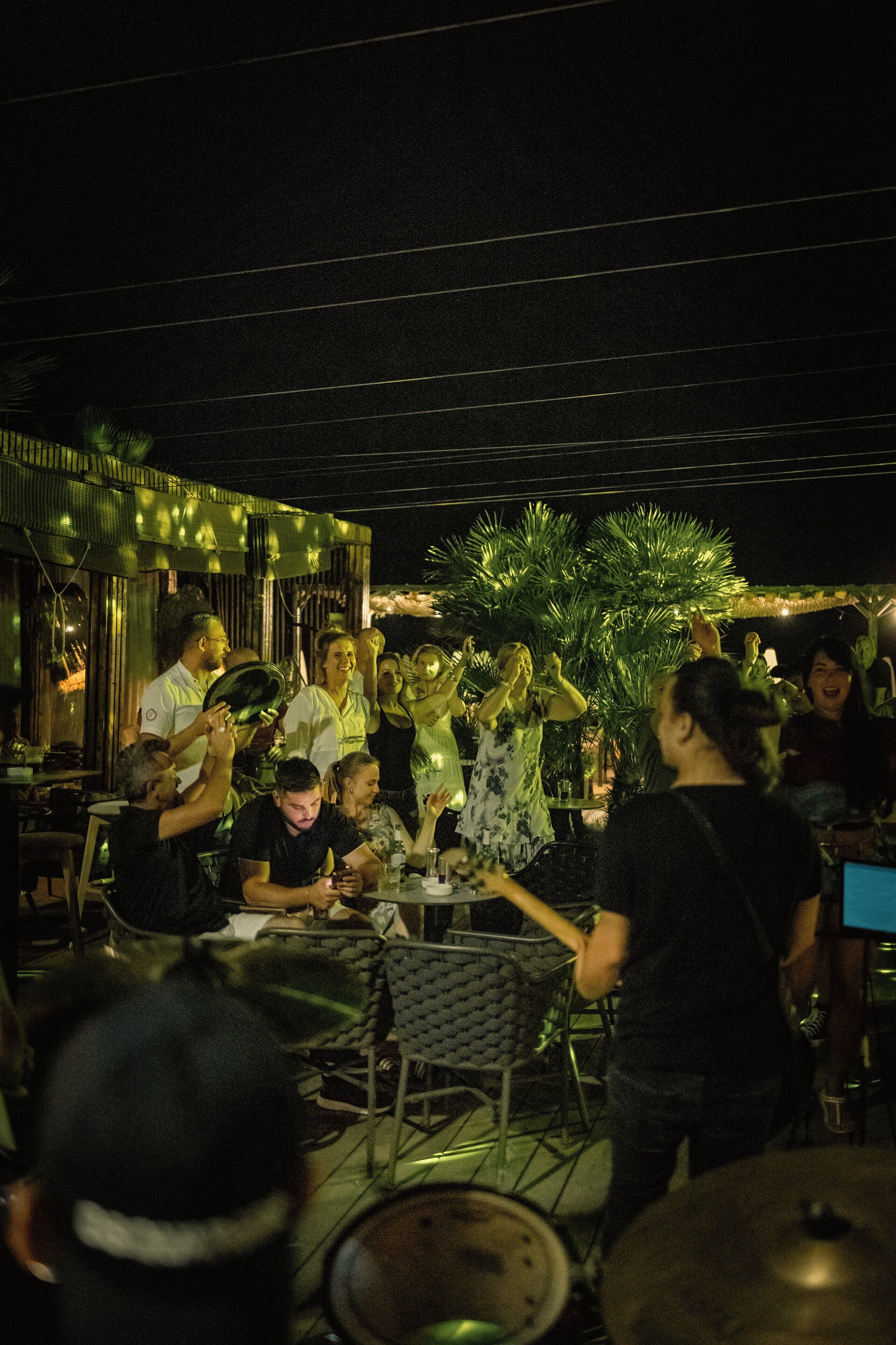 A group of people gathered around a table with musical instruments, suggesting a social event or gathering.