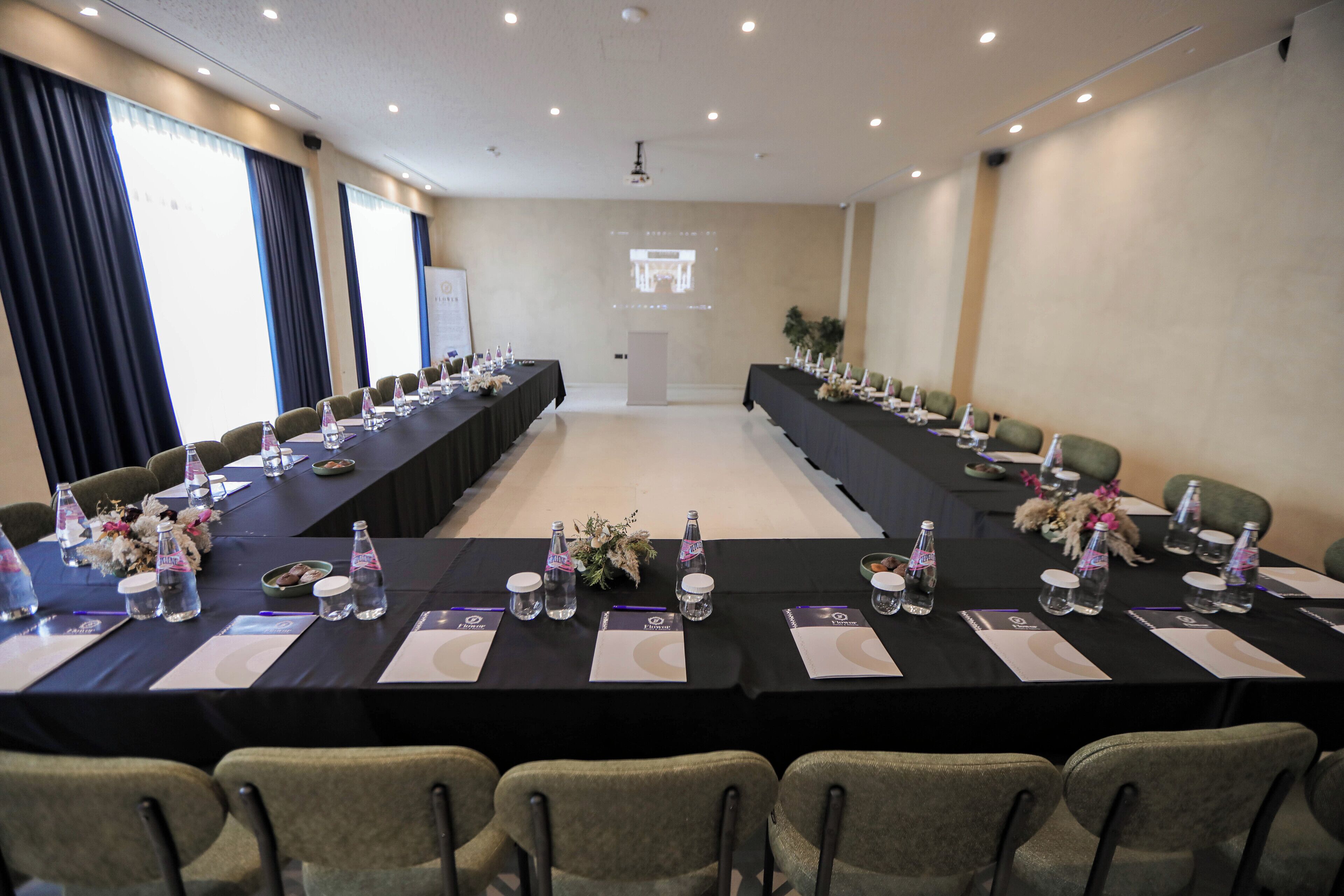 Una sala de conferencias con una mesa larga, sillas, botellas de agua y placas de identificación.