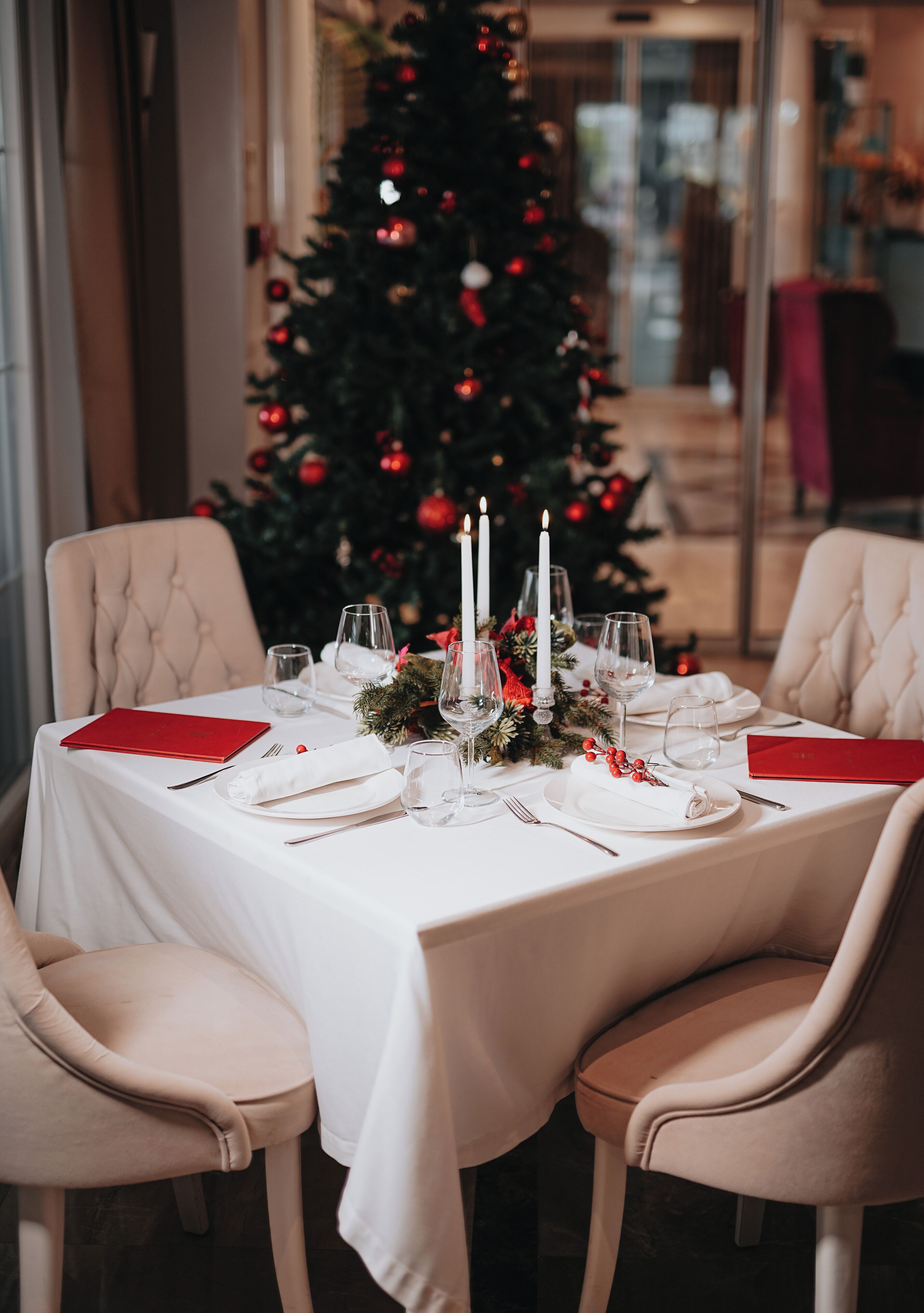 Mesa para cuatro personas dispuesta, con un árbol de Navidad al fondo.