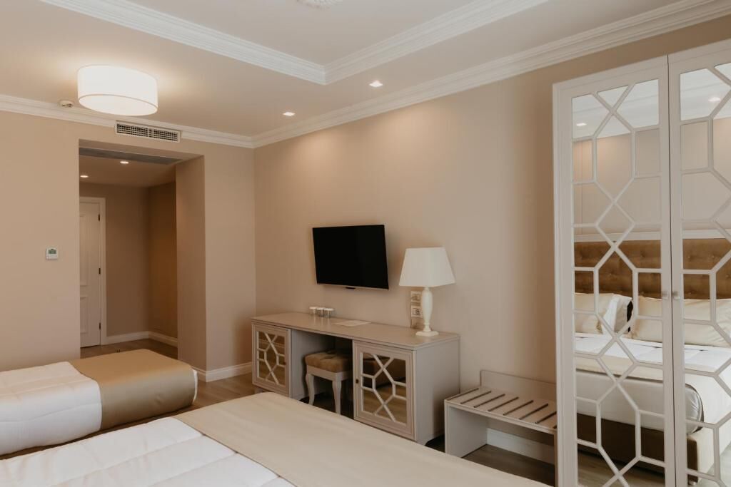 Een hotelkamer met twee bedden, een televisie, een bureau met lamp en een decoratieve scheidingswand.