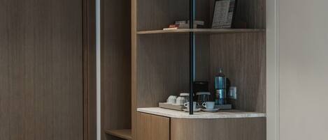 Een hoekhotelkamer met een ingebouwd houten schap, een deur en een koffieapparaat op het aanrecht.