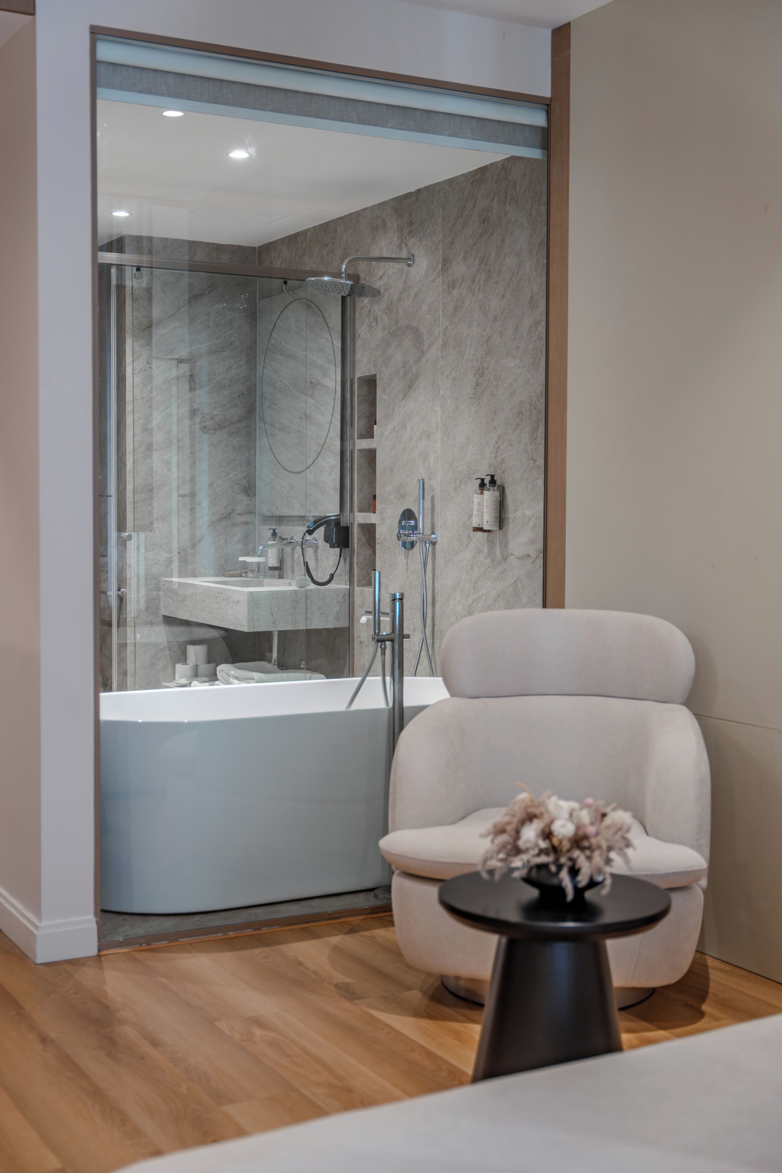 Une salle de bain moderne avec une douche à parois de verre, une baignoire blanche et un coin salon avec une petite table.