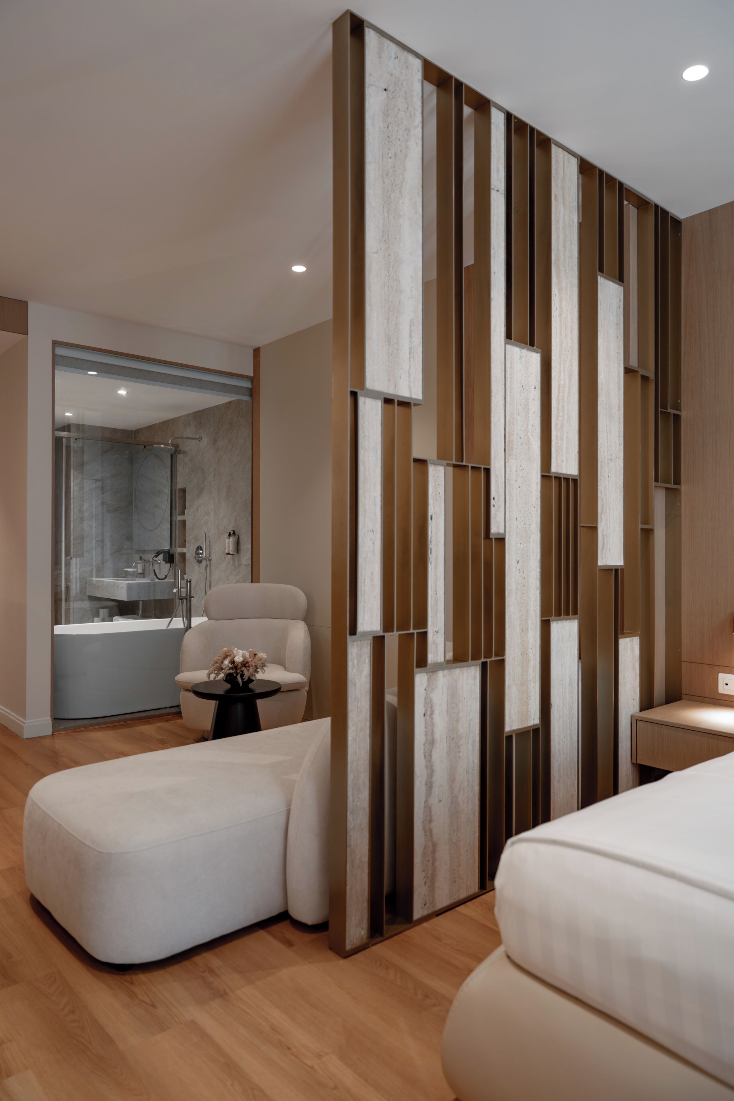 Un dormitorio moderno con una cama grande, una zona de estar y un baño con ducha y bañera.