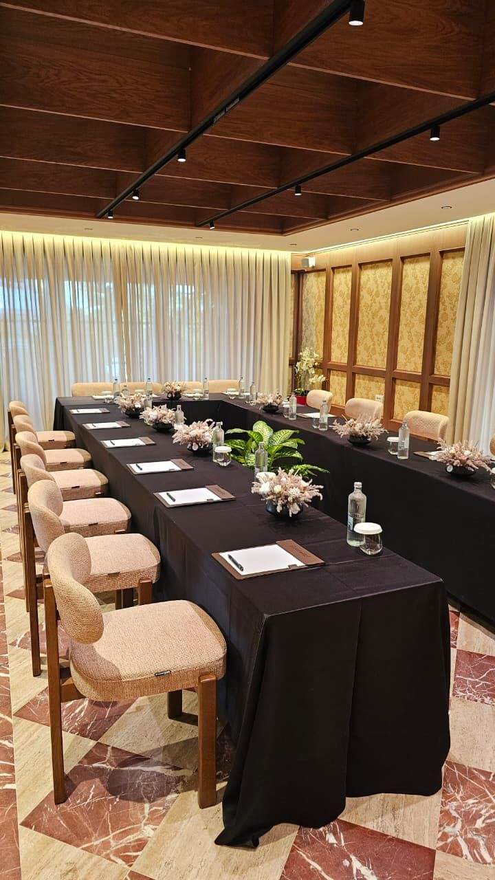 A conference room with a long table, chairs, and floral centerpieces.