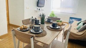 Ein Essbereich mit Holztisch, Stühlen, einer Kaffeemaschine, Tassen und einer Pflanze.