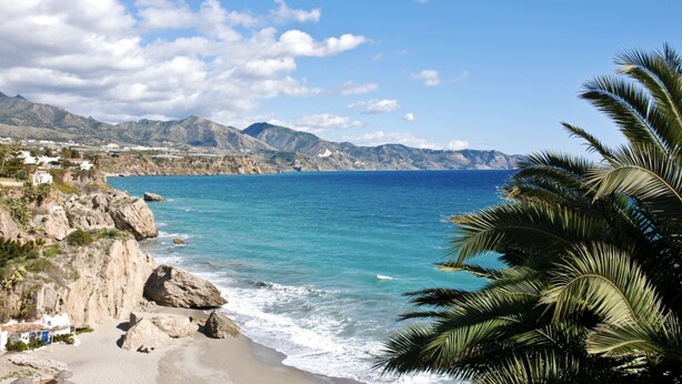 Eine Küstenlandschaft mit felsigen Klippen, einem Strand und einem klaren, blauen Meer.