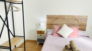Ein Schlafzimmer mit einem Bett, einem Nachttisch, einer Holzablage und einer Wand mit einem gemusterten Kopfteil.