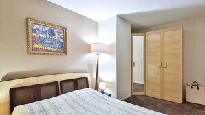 Una camera d'albergo con un letto, un comodino, una lampada, un quadro e un armadio.