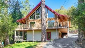 A two-story log cabin with a balcony, a garage, and a driveway leading to the entrance. - Walk to Pine Mountain Lake: Spacious Family Cabin (Groveland)