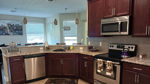 A kitchen with dark wood cabinets, stainless steel appliances, and a granite countertop. - Beautiful, spacious, family friendly private home! one (Port St. Lucie)