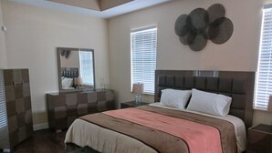 A bedroom with a large bed, a dresser, a mirror, and a decorative wall piece. - Beautiful, spacious, family friendly private home! one (Port St. Lucie)