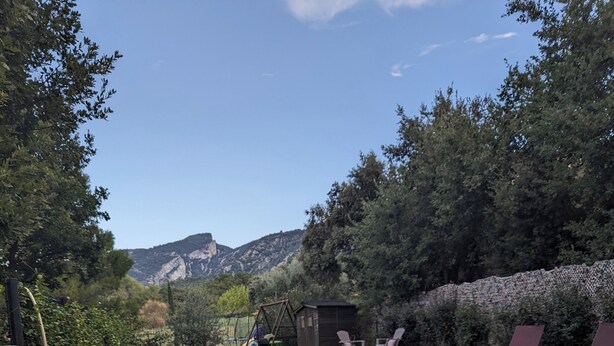 Un tavolo da pranzo con vista su una piscina, posti a sedere all'aperto e una bottiglia di vino.