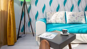 Una sala de estar moderna con un sofá color turquesa, una lámpara de pie verde y una mesa de centro con una revista y una taza.