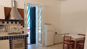 Una cocina con estufa, horno y comedor con mesa y sillas.