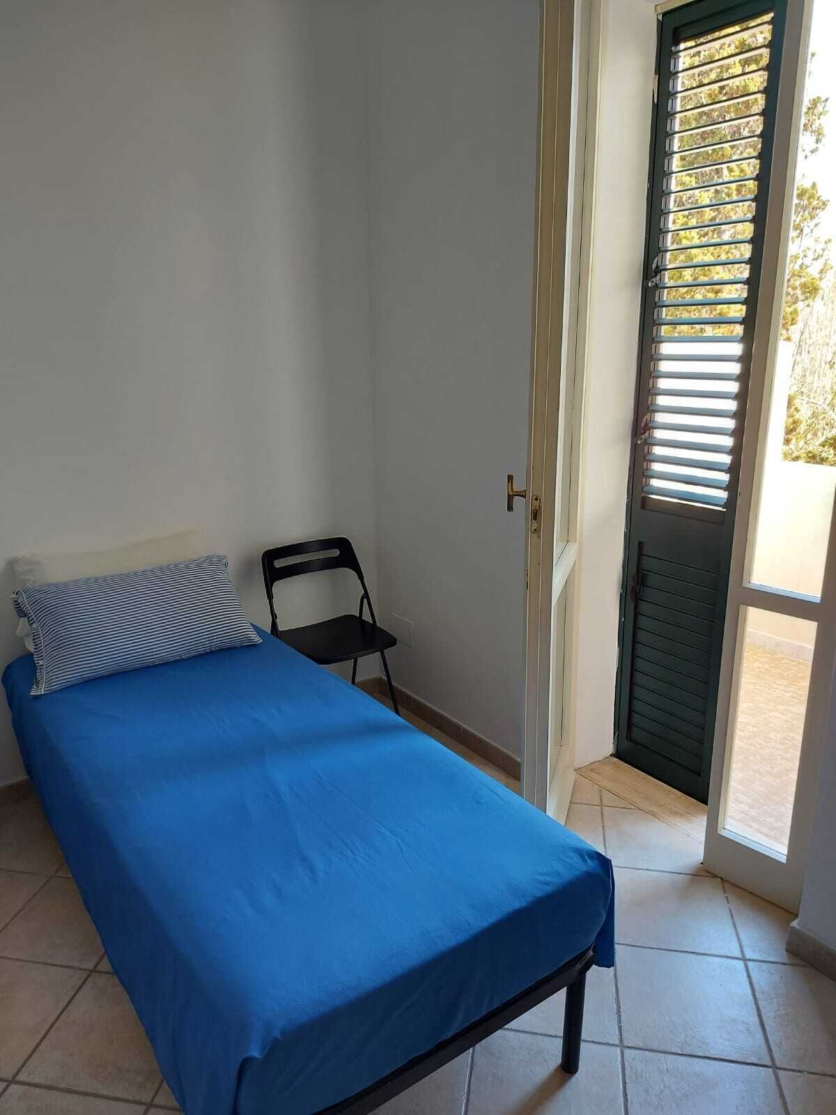 Quarto com cama, cadeira e porta com persianas.