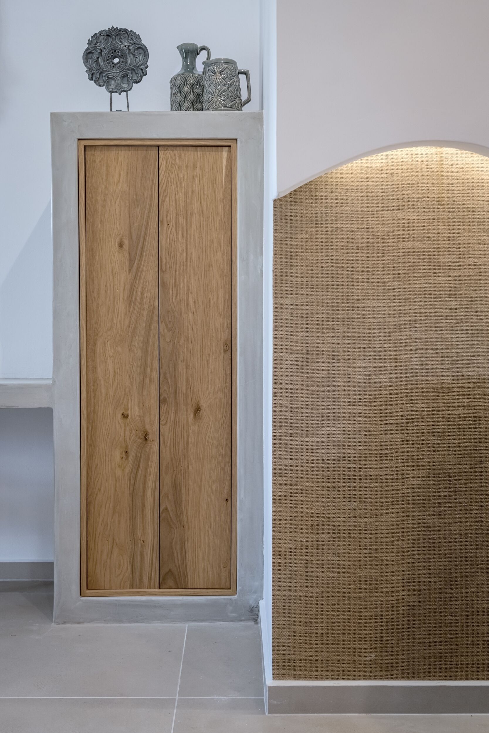 A wooden wardrobe with a textured fabric panel adjacent to it.
