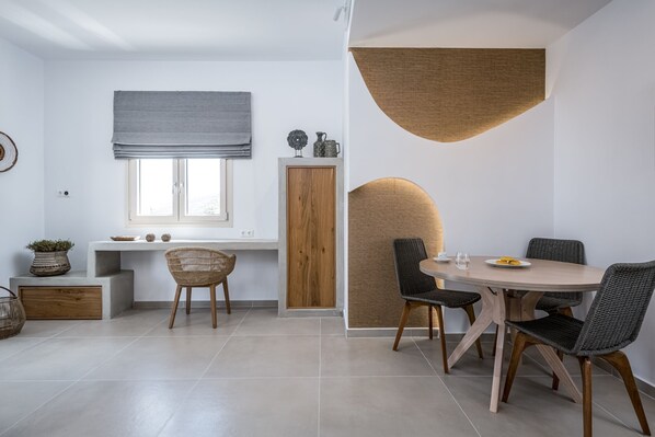 A modern dining area with a round table, wicker chairs, and a wooden cabinet.