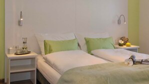 A bedroom with a large bed, a bedside table with a lamp, and a nightstand. - Schlotzeria Hotel I Cafe I Eis (Grenzach-Wyhlen)
