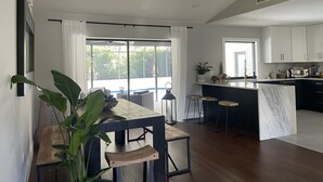 A modern kitchen with white cabinets, a marble island, and a dining area with a wooden table and chairs. - Modern near Siesta Beach (Sarasota)