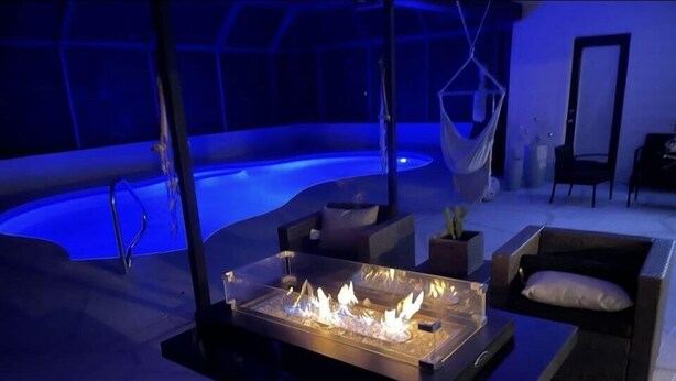 A modern indoor setting with a glass-top fire feature, seating area, and a pool. - Modern near Siesta Beach (Sarasota)