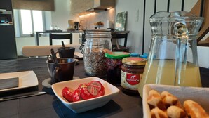 Eine Küchenarbeitsplatte mit Kaffeemaschine, Gewürzgläsern, einer Schüssel mit Paprikastreifen und einem Saftkrug.
