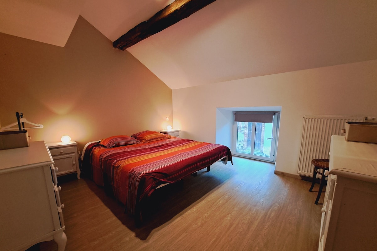 Un dormitorio con cama, mesitas de noche, ventana y radiador.