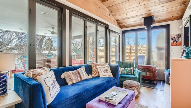 Un salón acogedor con un sofá azul, techo de madera y ventanas amplias.