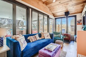 Un soggiorno accogliente con un divano blu, un soffitto in legno e ampie finestre.