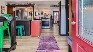 Una cocina moderna con una isla central, una puerta roja y una guitarra colgada.
