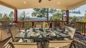 A covered outdoor deck with a table set for dining, a grill, and a ceiling fan. - Wildlife Watching & Mtn Views: Luxe Ruidoso Escape (Ruidoso)