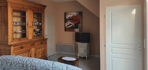 A bedroom with a wooden cabinet, a painting, a television, and a door.