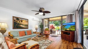 A living room with a sofa, chairs, a television, and a ceiling fan. - KKSR#8101 GORGEOUS 2 BEDR, GROUND FLOOR CORNER, REMODELED, AIR CONDITIONING (Kailua Kona)