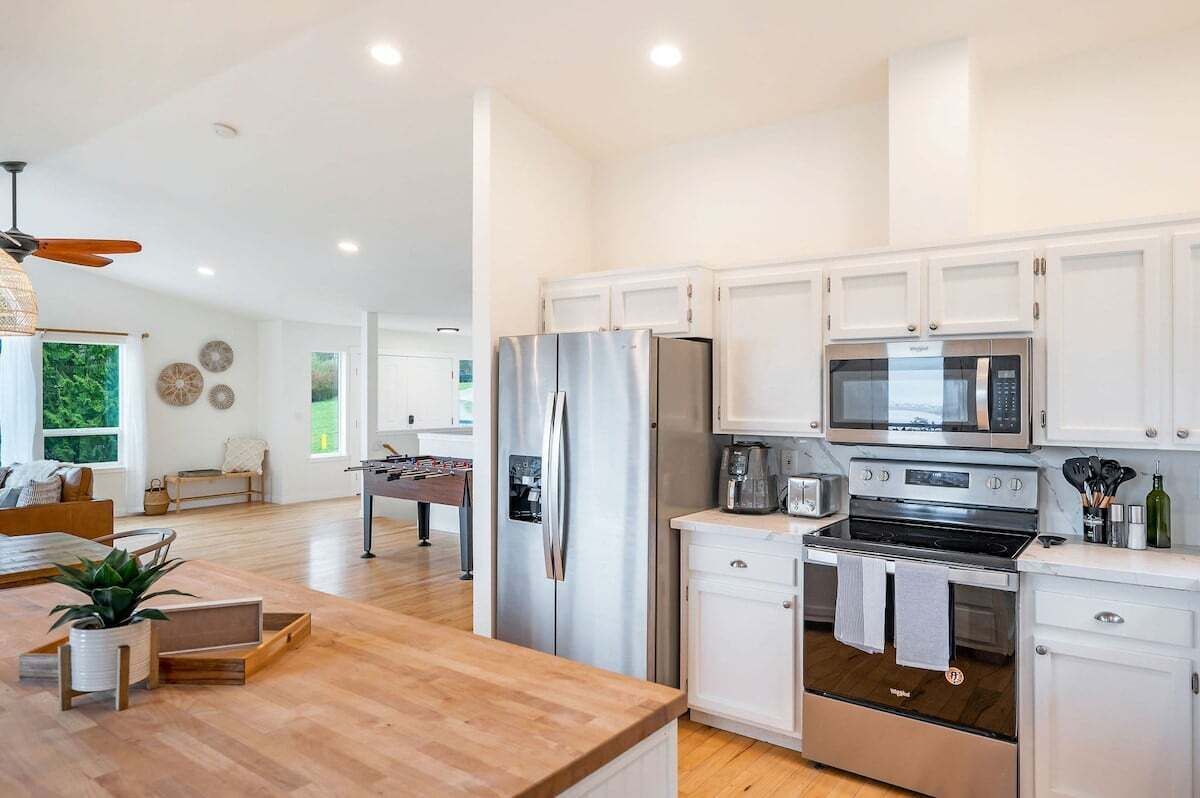 A modern kitchen with white cabinetry, stainless steel appliances, and a wooden countertop.