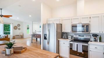 A modern kitchen with white cabinetry, stainless steel appliances, and a wooden countertop.