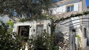 A white building with a stone wall, a red potted plant, and a metal gate. - Aix en Provence has quiet house 5m from the city center on foot (Aix-en-Provence)