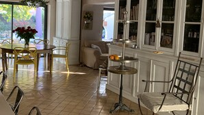 A dining area with a chandelier, a round table with chairs, a bookshelf, and a window with a view of greenery. - Aix en Provence has quiet house 5m from the city center on foot (Aix-en-Provence)
