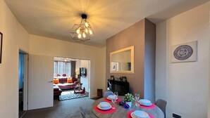 A dining area with a round table set for four, a modern chandelier, and a fireplace. - Johnson House - Contractors, Families, Holidays (Cleethorpes)