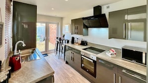 A modern kitchen with stainless steel appliances, a large window, and a sliding door to an outdoor area. - Johnson House - Contractors, Families, Holidays (Cleethorpes)