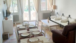A dining area with a table set for four, a sofa, and a hanging light fixture. - A bit of straw (Cagnes-sur-Mer)