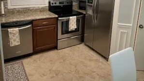Una cocina con armarios de madera, un refrigerador de acero inoxidable, horno empotrado y encimera de granito.