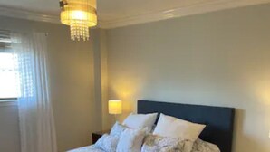 Un dormitorio con una cama, una mesita de noche, una lámpara y un candelabro.