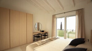 A bedroom with a large bed, a desk with chairs, a mirror, and a view of the outdoors through a sliding door. - Stunning new villa with beautiful lake view (Bardolino)