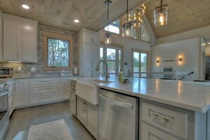 A modern kitchen with white cabinetry, a large island, stainless steel appliances, and pendant lighting. - 4 Dancing Bears|Mtn Views+Hot Tub+ Design (Blue Ridge)