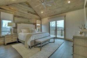 A bedroom with a large bed, a bench, a nightstand, a dresser, and a ceiling fan. - 4 Dancing Bears|Mtn Views+Hot Tub+ Design (Blue Ridge)