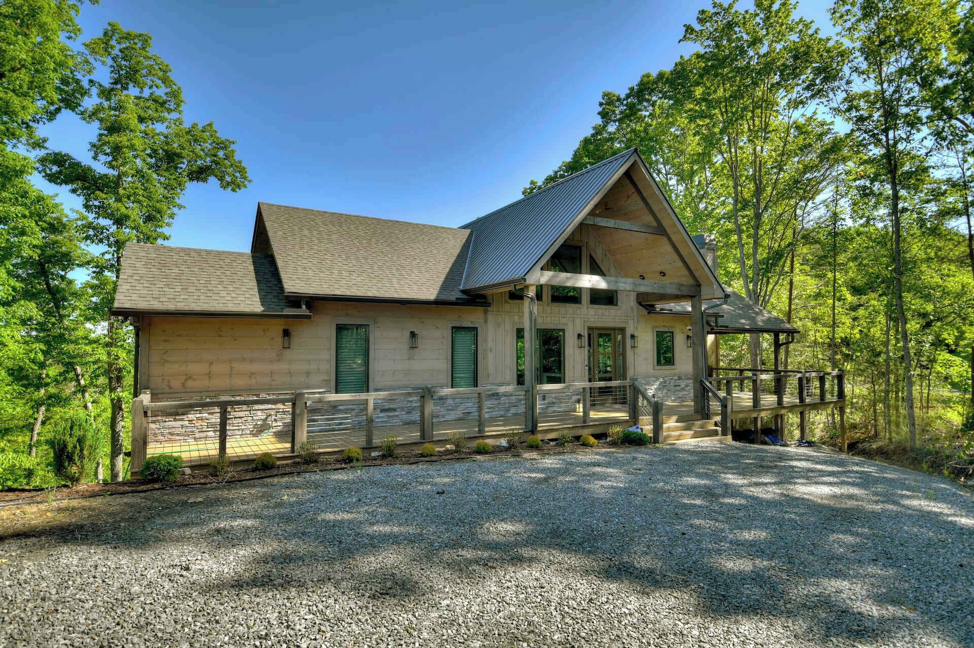 Une cabane en bois à deux étages, avec une allée en gravier et une clôture en bois.
