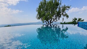 A clear blue infinity pool with a tree in the center, surrounded by a blue tiled wall. - Villa Melani (Oriovac)