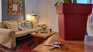 Ein Wohnzimmer mit einer Couch, einem Couchtisch und einer großen Küstpflanze.